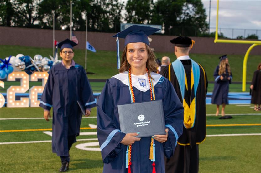 Students graduate outside on a football field
